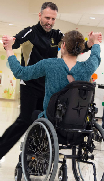 Go dance guest in a wheelchair dancing with an instructor
